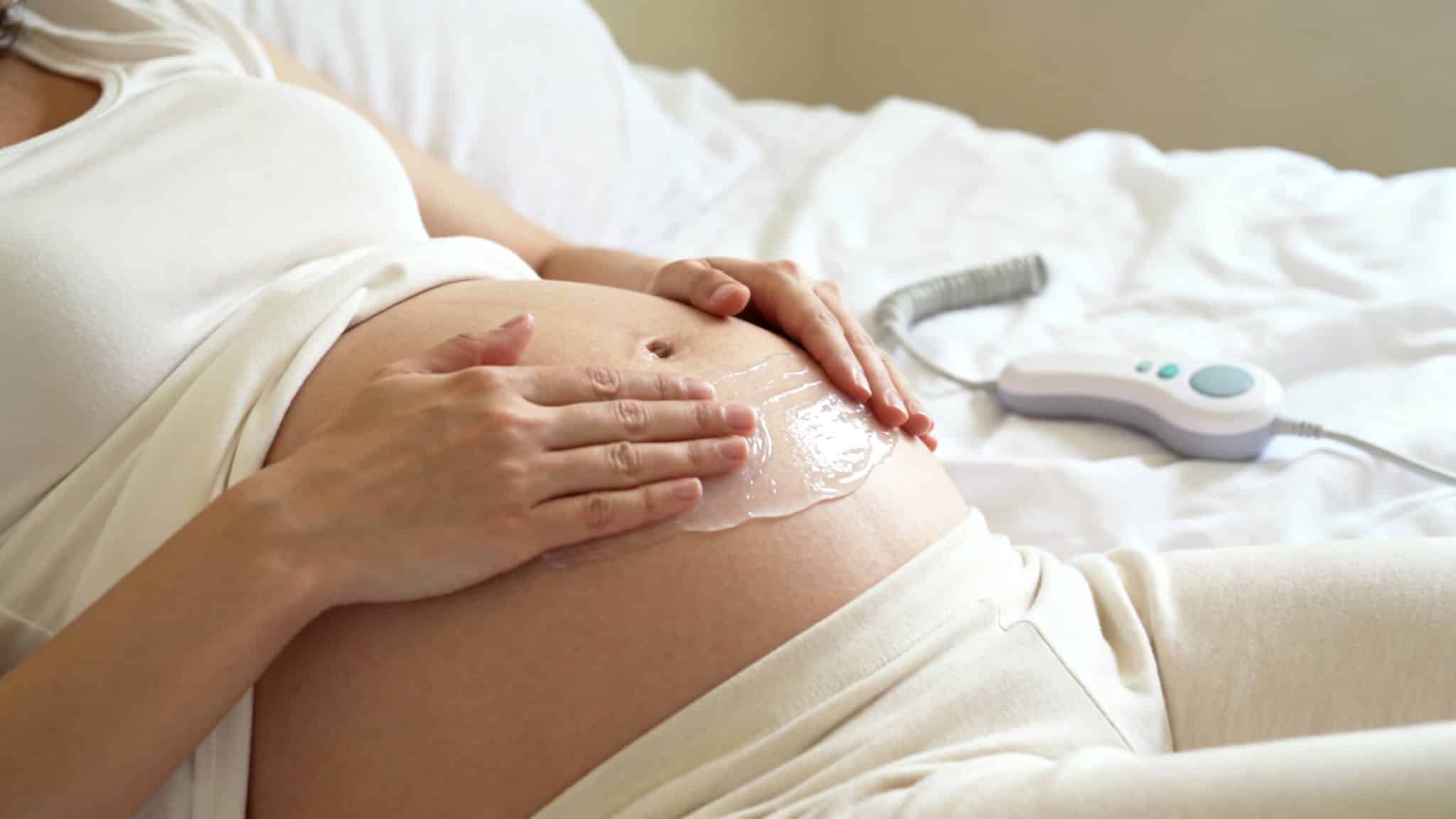 Application du gel ultrason sur le ventre avant utilisation du doppler fœtal, geste précis et doux