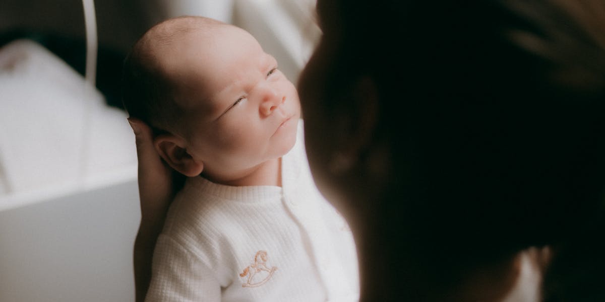 Maman tenant son bébé dans les bras, regard pensif